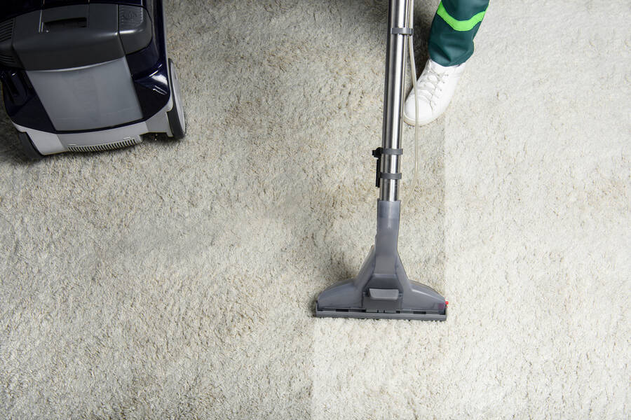 A vacuum leaving a visibly cleaner track across a cream carpet